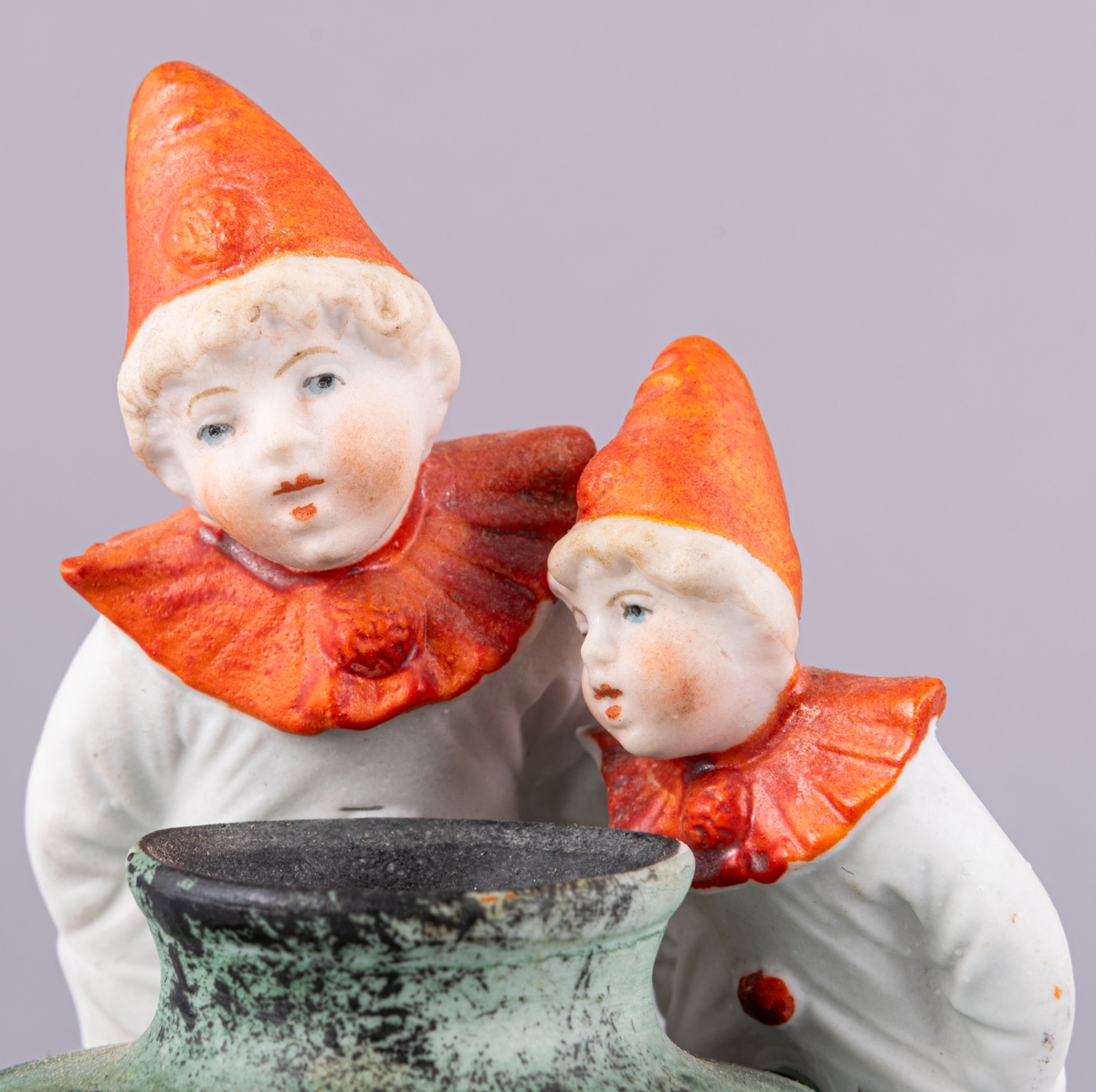 Bläckhorn i keramik, föreställande två små clowner i vitt och rött vid ett grönt bläckhorn. Reklamtext på hornet.