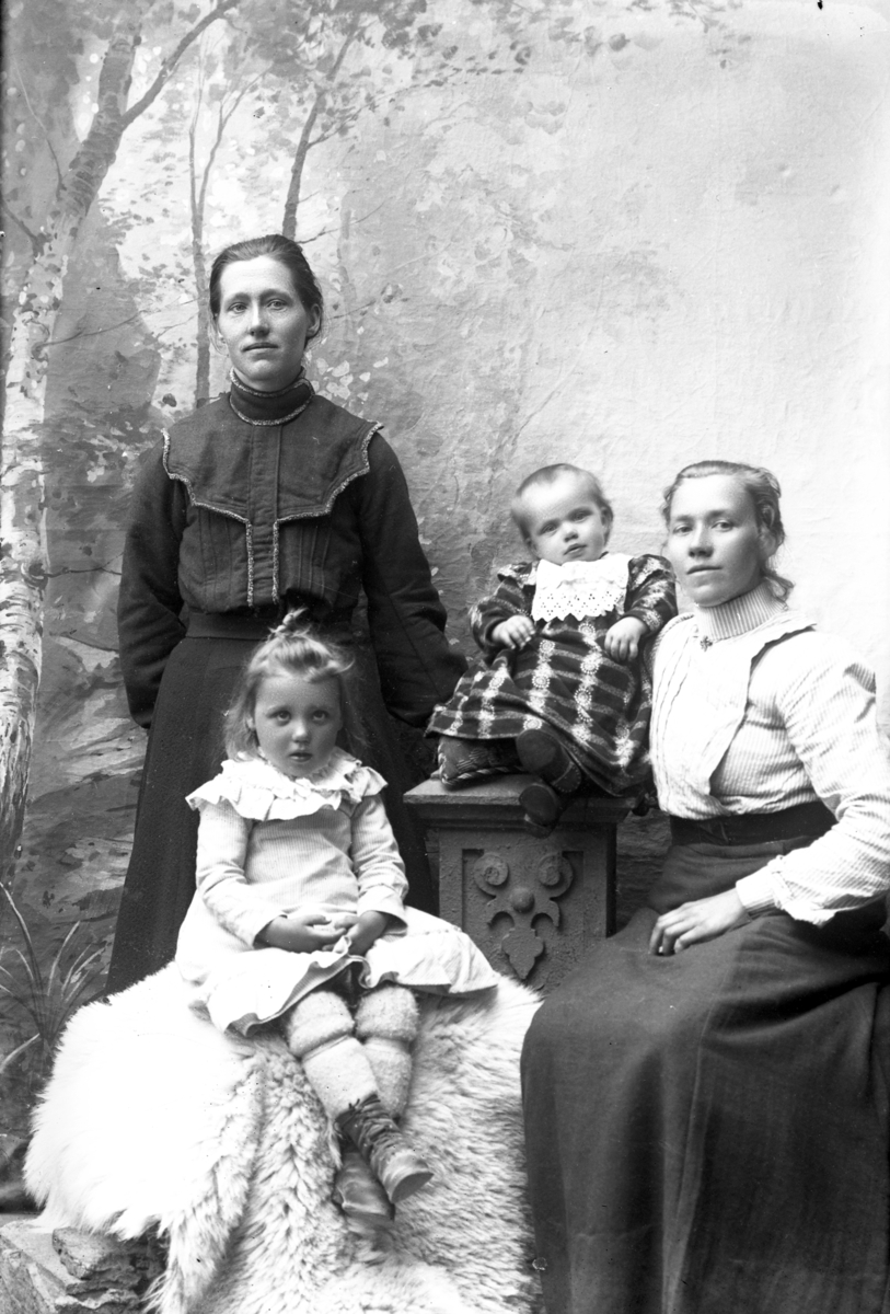 Atelierfoto.Gruppebilde (familiebilde?).En eldre kvinne, en yngre kvinne og to små jenter.