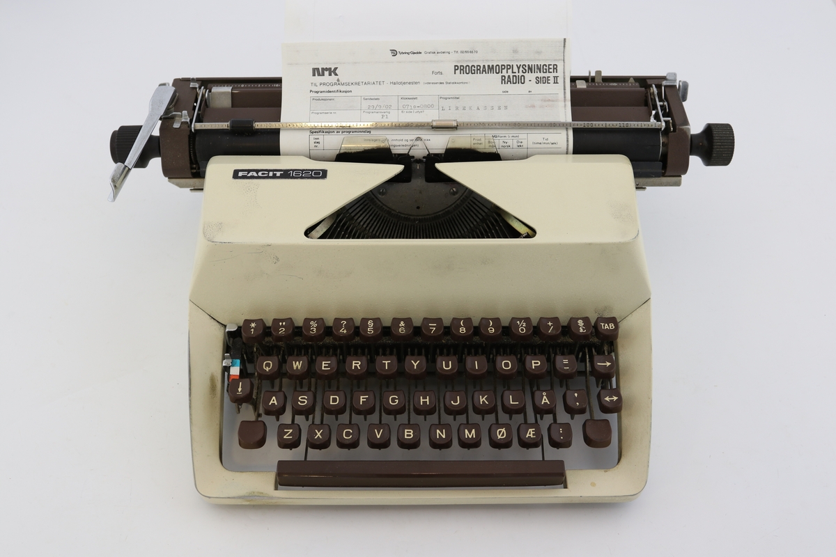 Kremhvit skrivemaskin med svart koffert. Ark i skrivemaskinen med programopplysninger for radio.