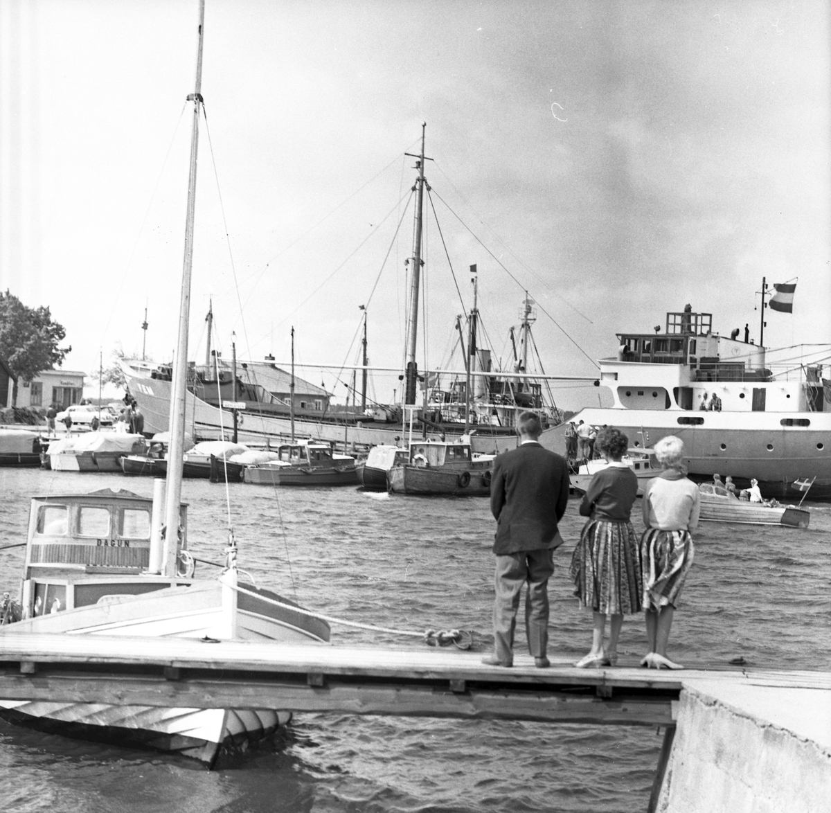 En man och två kvinnor tittar på fartyget "FEM" i Öregrunds hamn