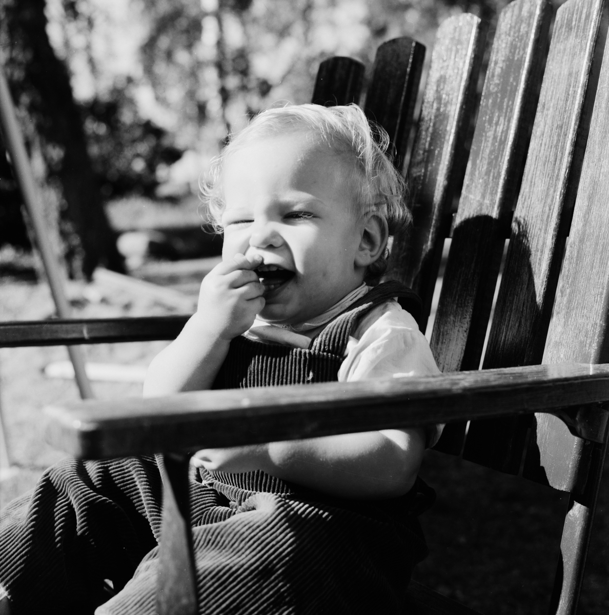Litet barn sitter i trädgårdsstol, Uppland 1961
