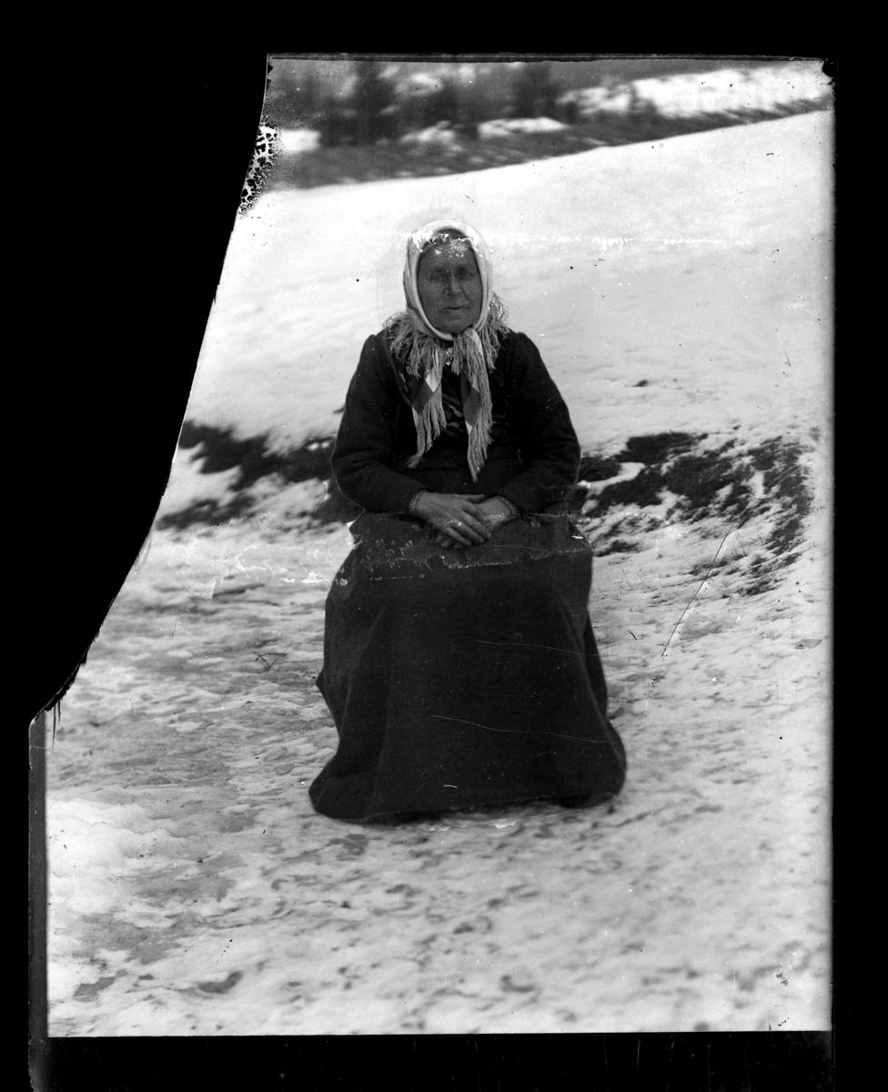En eldre kvinne sitter ute på en stol i snøen.Vinter.