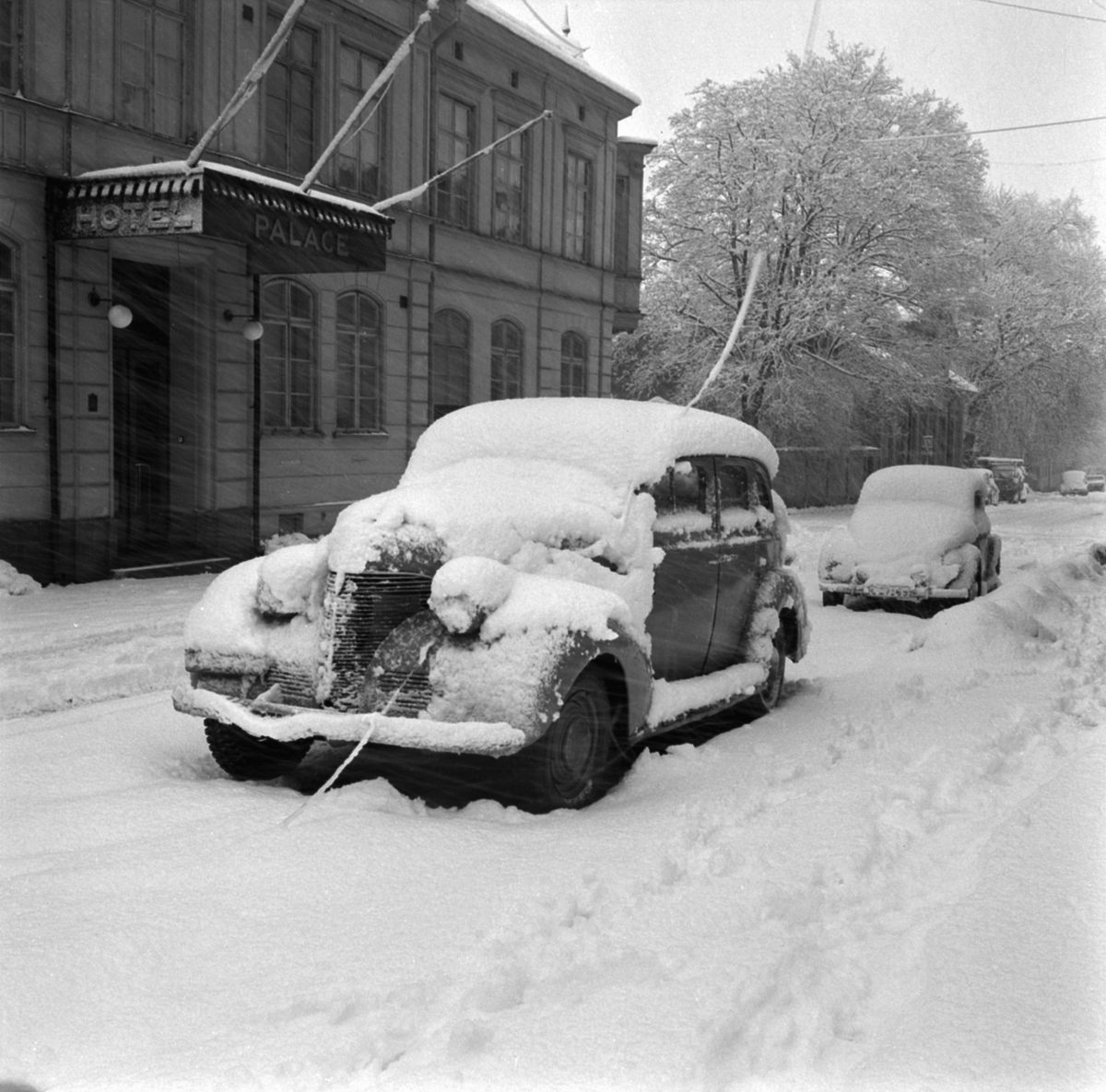 Ymnigt snöfall i Linköping. Just detta särskilt kraftiga snöoväder drabbade staden under februari månads sista dagar 1954. Här oplogat framför Hotell Palace vid Kungsgatan.