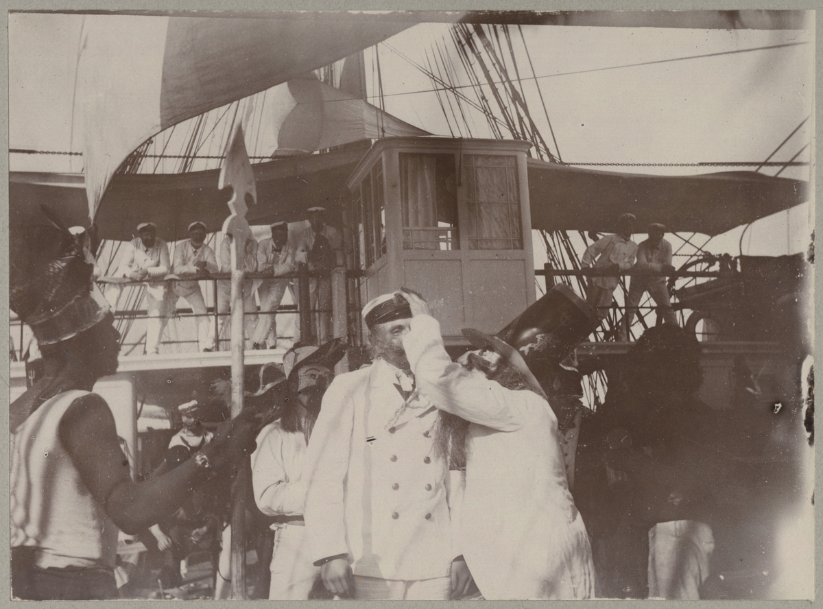En sjöman undersöks av Neptuns läkare under linjedopet ombord på Balder. I bakgrunden syns Balders befäl i vita uniformer stående på kommandobryggan som njuter skådespelet.