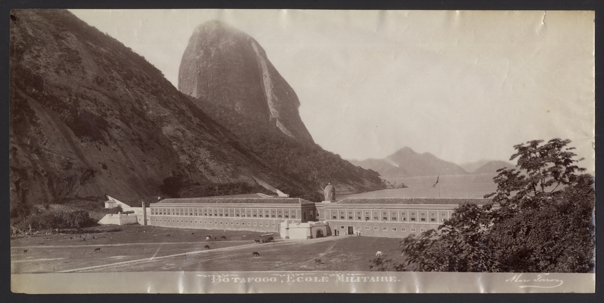 Bilden föreställer en vy över viken Baie de Botafogo i Rio de Janeiro med militärskolan i förgrunden och Sockertoppen i bakgrunden.