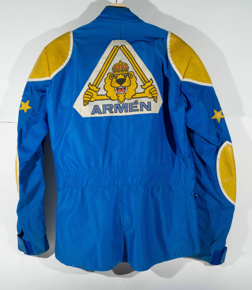 Mellanblå MC-ställ med gula och vita detaljer. På vänster sida av bröstet på jackan "H AB Malugn Sweden"  och på höger sida ett trekantigt märke "Armén".  På ryggen ett stort trekantigt märke "Armén". På byxorna "Arméns Lejon".