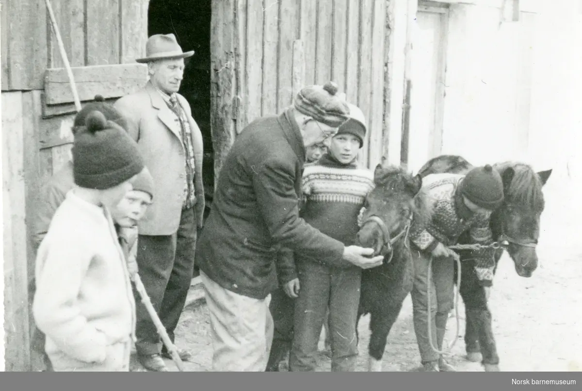Lars H. Lende midt i bildet med to ponnier, fem barn, Nils Arne Leikvoll til høyre, og en mann.