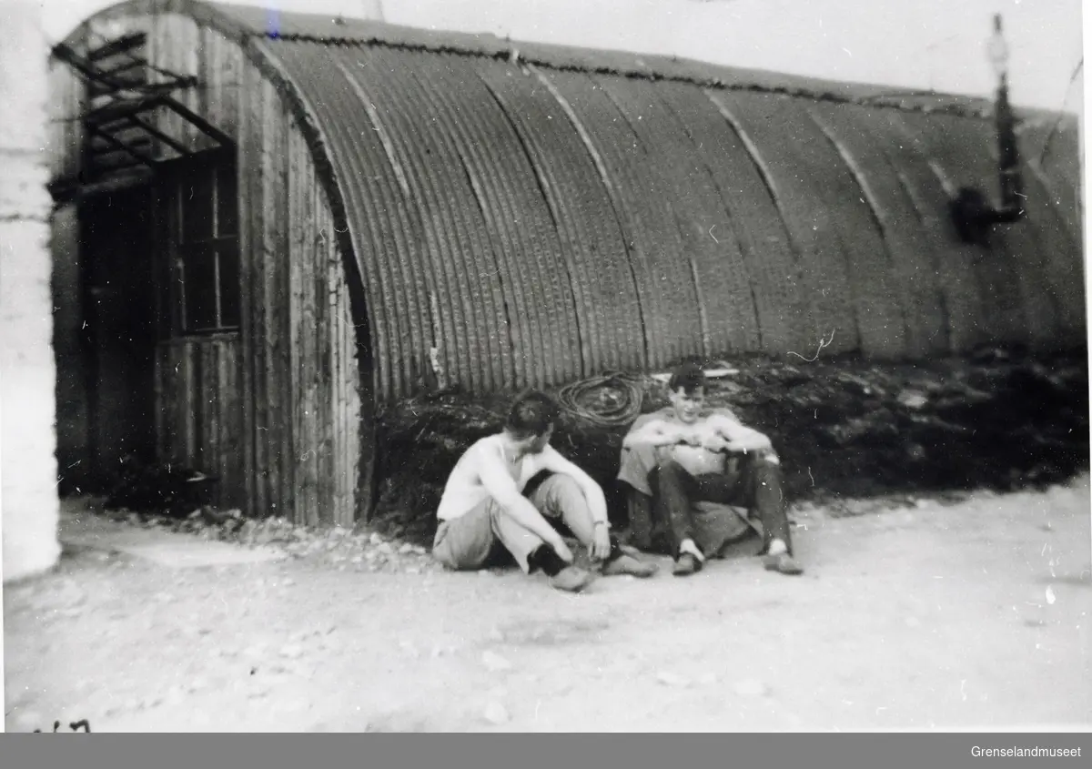 To personer sitter utenfor en Nissenbrakke og slapper av. Den første flysikring stasjonen etter krigen (1947). 