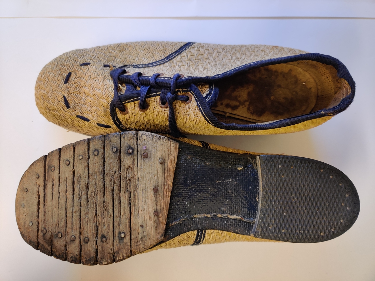 Sko laget av vevd papirstrie med tresåle og snøring. Hælen har et tynt lag ytterst som ser ut til å være gummi eller lignende. Forstykket av sålen er laget av tre skåret på sikksakk-vis, noe som har gitt sålen mer fleksibilitet (tilsvarende en liknende sko hos Glomdalsmuseet: GM.031640).