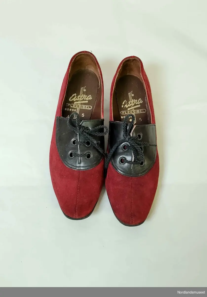 Snøresko til dame med hæl. Skoen er laget i rødt semsket skinn med et felt i svart skinn i front. I skoene er det lagt sydde såler som kan være hjemmeproduserte. Str. 5. Blå og hvit original skoeske.