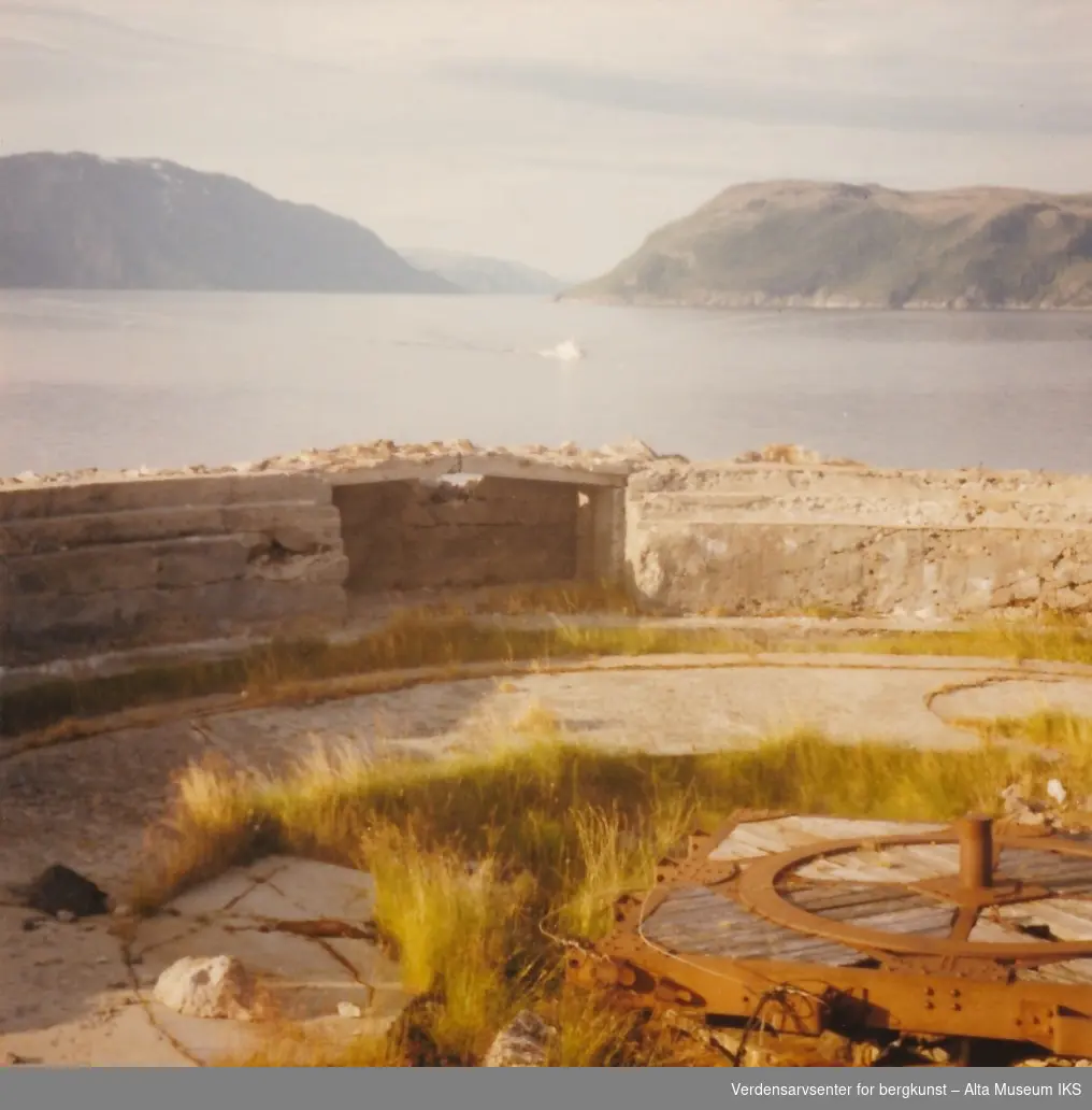 Storekorsnes i Altafjorden. Rester av Tysk militæranlegg. Fjell, fjord og en båt i bakgrunn.