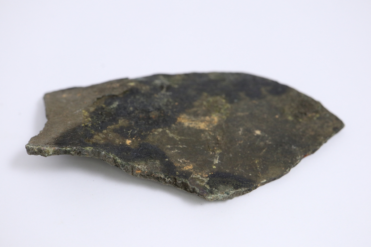 Brandskadat fragment av bronsgryta. Bukbit.