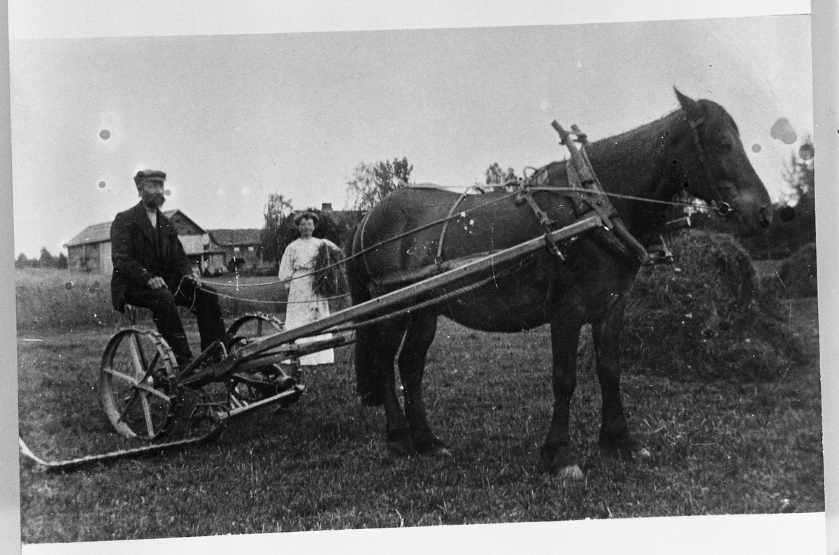 Johannes Skinderviken sitter på slåmaskin som trekkes av en hest. Marie Skinderviken litt bak.