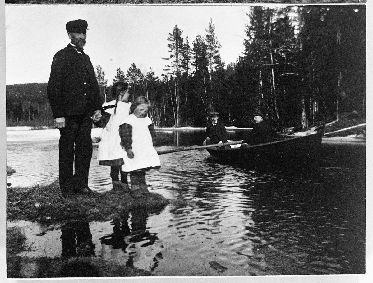 Personer ved et tjern. Fra venstre Johannes, Alfhild og Lill Ann Skinderviken. I båten Mathias og Gustav Skinderviken. April 1911.