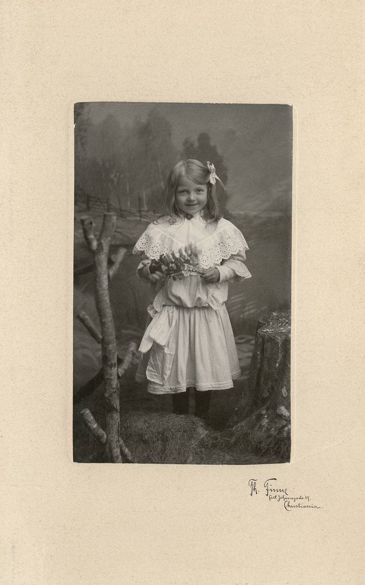 Studio-portrett av en liten pike med en kvist i hånda