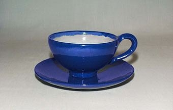 Blå kaffekopp med fat i lergods med vit insida på koppen.