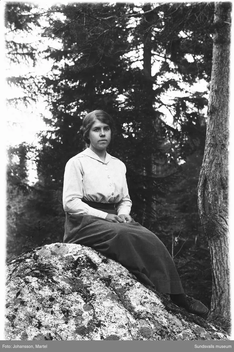 Porträttbild av Johanna "Hanna" Johansson, Sörfors, sittande på en sten i skogsmiljö.