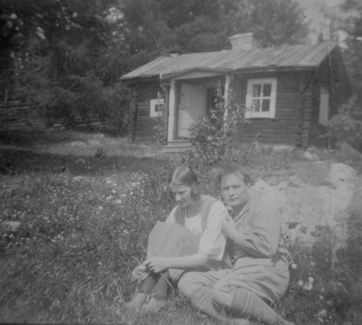 Albert Viksten och hans första fru i gröngräset i sluttningen nedanför ett litet torp.