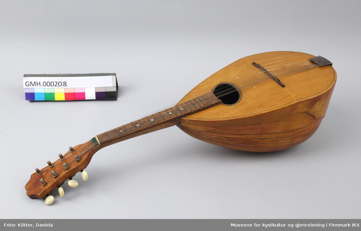 Mandolin med pæreformet resonanskasse, avvinklet lokk, en sterk hvelvet bunn, kort hals og åtte strenger. Instrumentet er produsert i Italia.