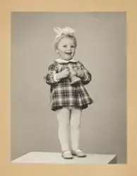 Portrett liten jente stående på en boks med leke i hendene