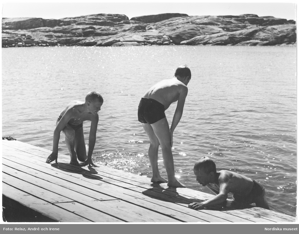 Tre pojkar badar vid en brygga i Fisketången.