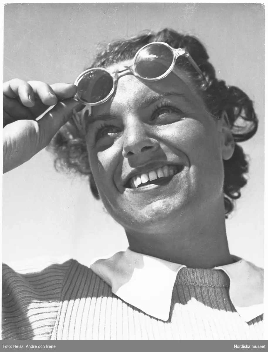 Porträtt av en leende ung kvinna i solglasögon på pannan.