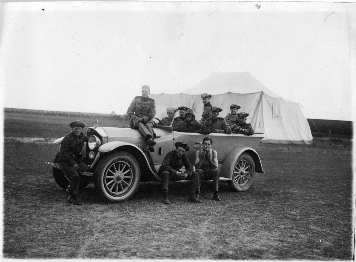 Flygsoldater i Flygkompaniets bil framför tälthangar på Rinkabys flygfält, 1925.
Under övning för Flygkompaniet. 11 män vid bilen.

På fotbrädan, iklädd hatt, sitter Helmer Andersson.