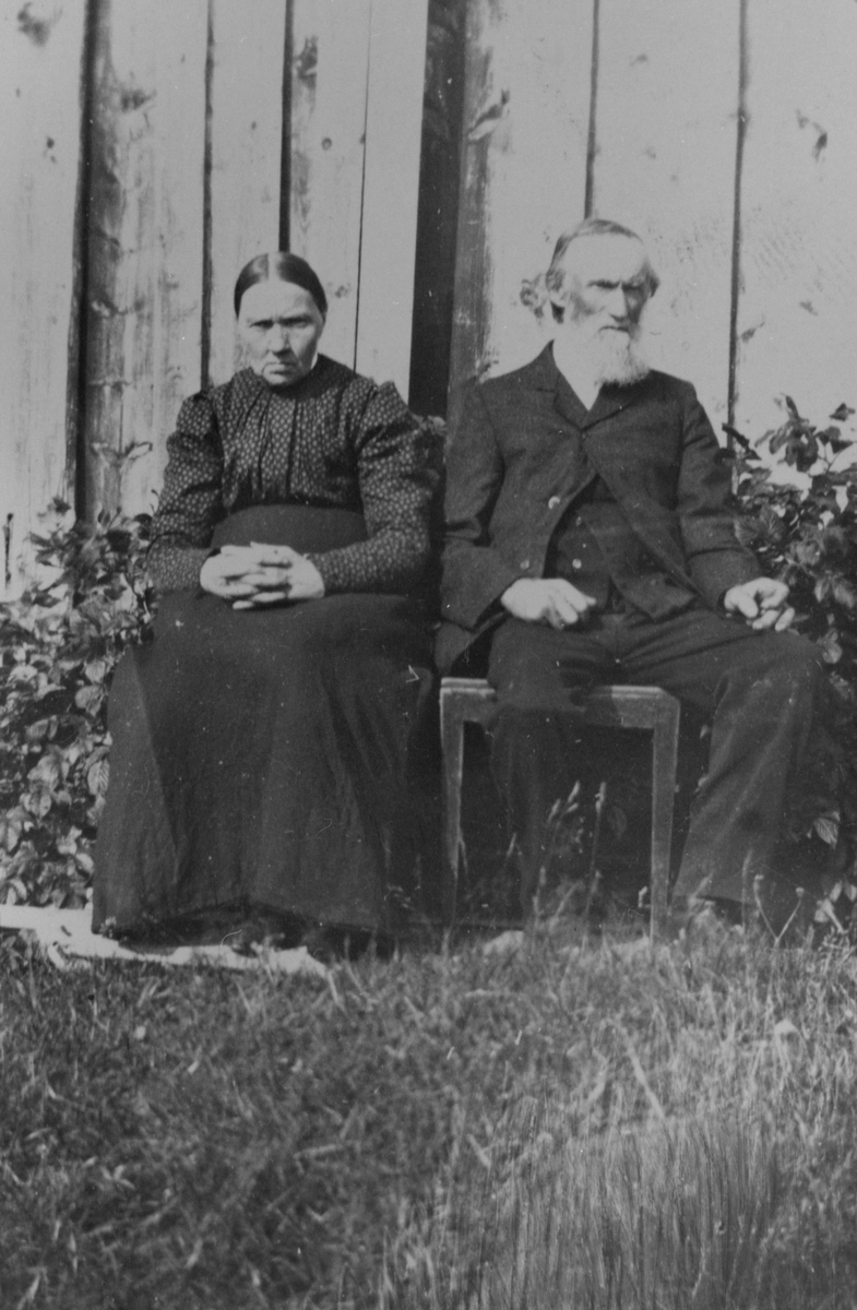 Ekteparet Jakob Andreas Nilsen Hestnes og Andrea Olava Andersdatter sittende ved husveggen.