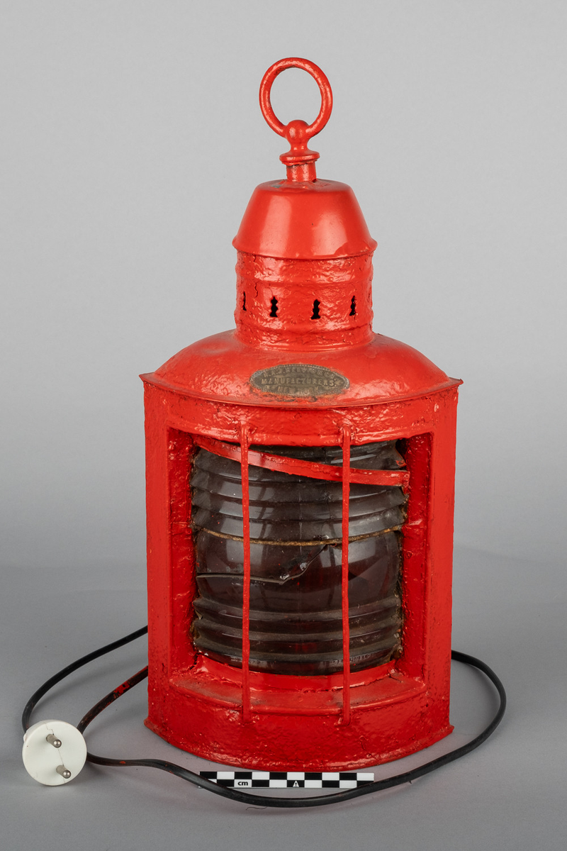 Babord lanterne med hank på toppen og feste for veggoppheng på bakside og ventilasjonsåpninger i toppen. Omgjort til elektrisk. Linse er knust.