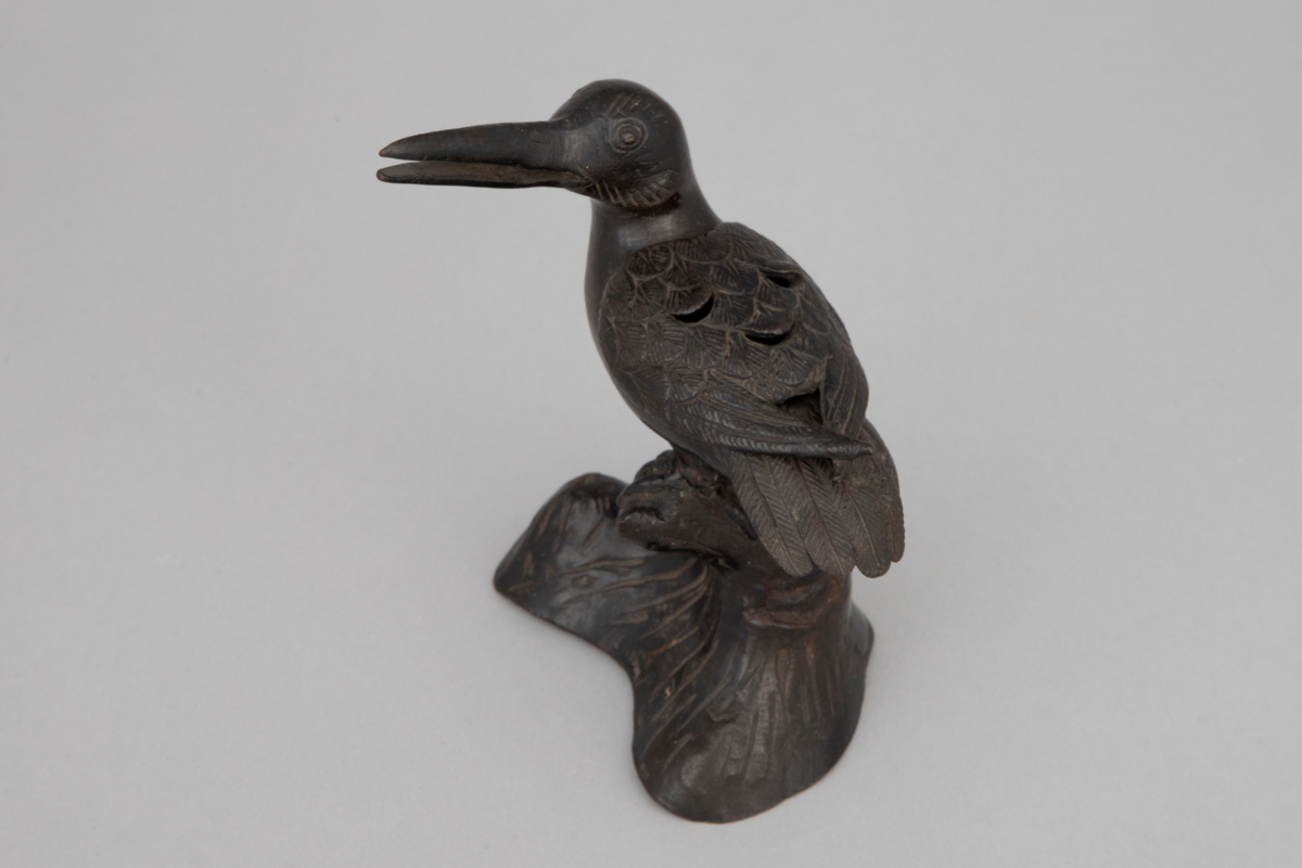 Røkelseskar utformet som fugl i støpt bronse. Løst vingeparti som kan løftes av som lokk. Fuglen sitter på hvelvet, svunget fotstykke. Patinert, mulig lakkert. Vinger, haleparti og deler av hode er siselert.