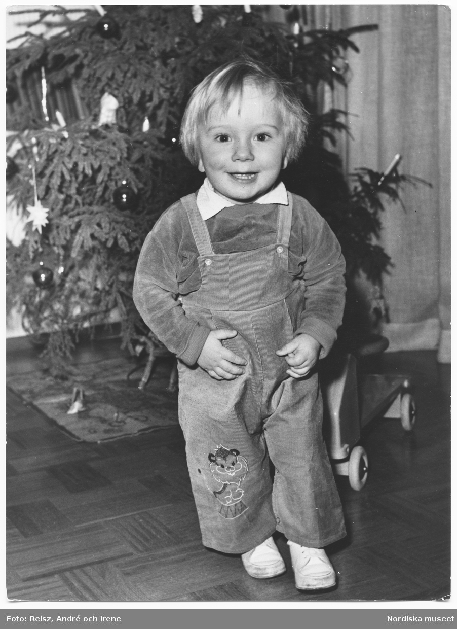 Helfigursporträtt av ett barn vid julgranen.
