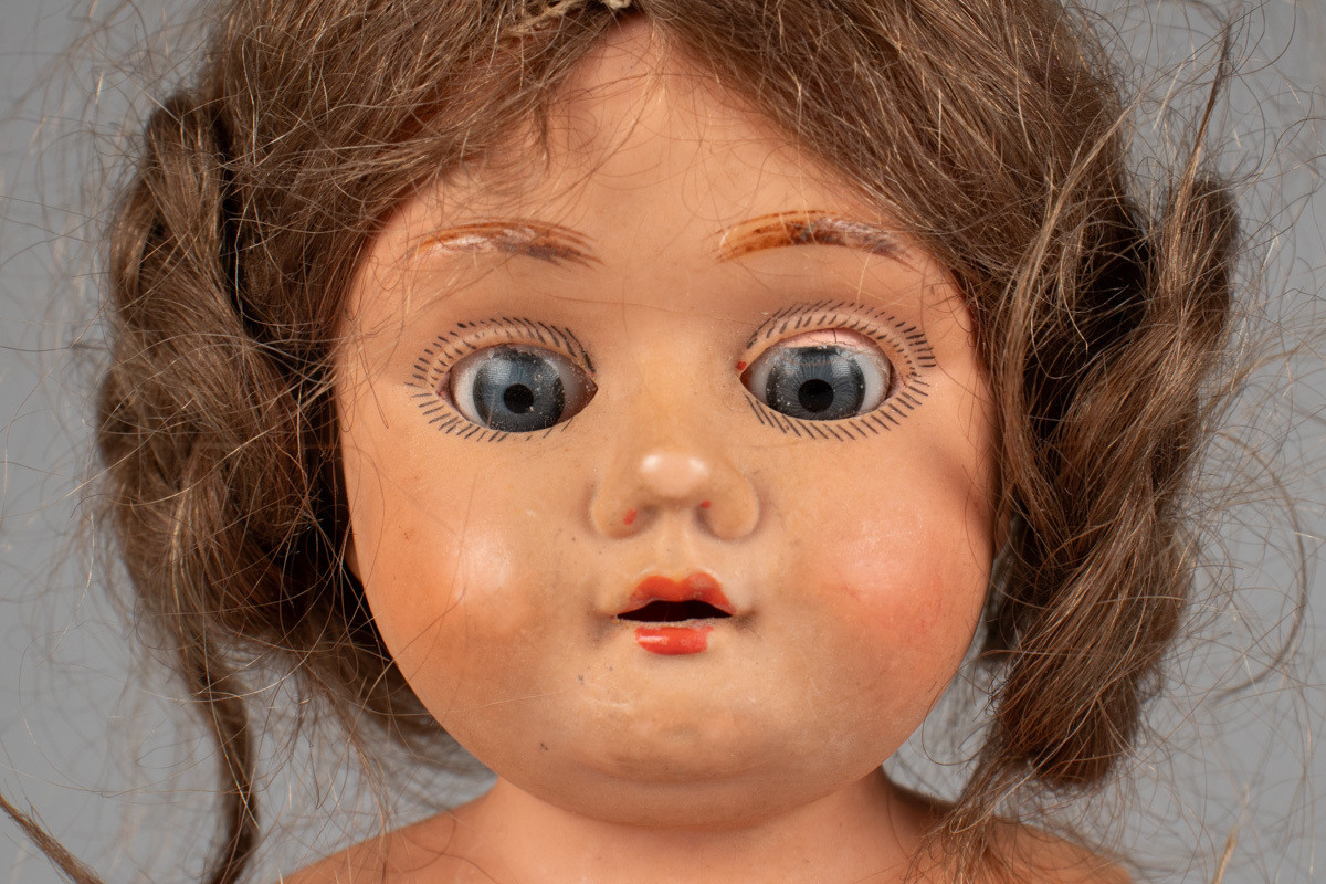 Dukke med  tett stoppet tøykropp. Tøykroppen er fra 1882, da dukken ble kjøpt ny. Den er reparert flere ganger, og nye tøystykker er montert på. Hodet og armene var opprinnelig av porselen, men de ble ødelagt i lek. I 1919 arvet Dorotheas datter dukken, og i den sammenheng fikk den nytt hode i det moderne stoffet celluloid. Dukken har øyne som kan åpnes og lukkes, og langt brunt hår i fletter.