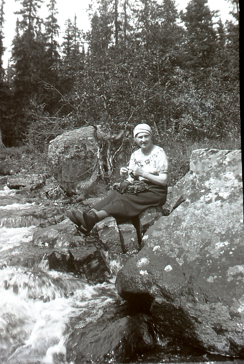 Dame ved elv
Ved Bugen på nedsiden av Hovdebrua. Bugen er lokalt navn på bekken mellom Hovdebrua og Bukkemyrbrua i Børtnesødegaardene. Her er det fint å fiske med flue eller mark. Caroline Lunde Sveinsson, 1878-1977. Hun var fra Lunde gård, Trømborg i Eidsberg, Østfold og ble i 1904 gift med Olav Sveinsson, f. Høllo, 1854-1927.
