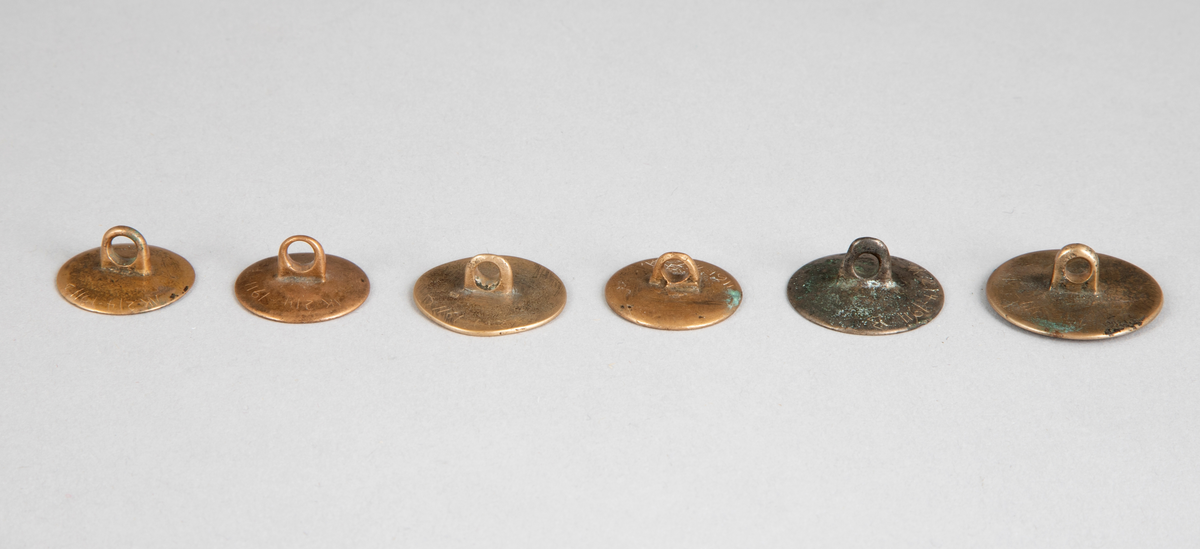 Seks ulike støpte knapper i messing med graverte blomsterornamenter.