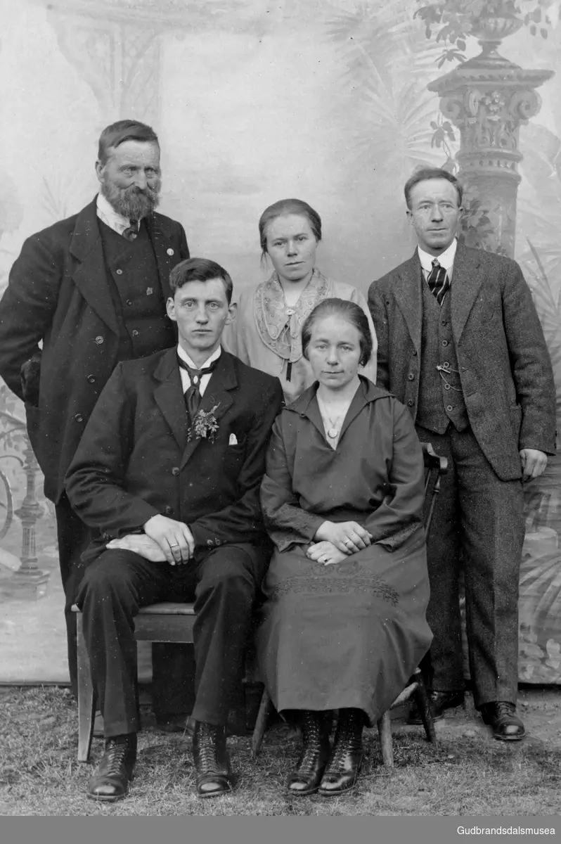 Bak f.v.: Erland Kvåle (f. 1853), Tea Kummen (f. 1893) og Ivar Kummen (f. 1879).  
Fremst brudeparet Nils Bakkeberg (f. 1896) og Anne Bakkebberg (f. Kummen 1896)
