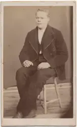 Portrettbilde av en ung mann sittende på en krakk. Nikolai G