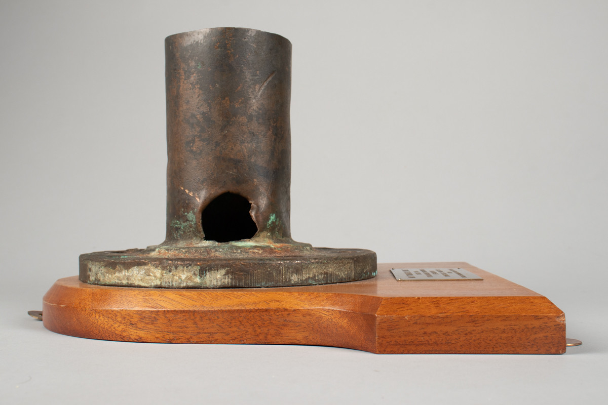 Metallrør montert på treplate med plakk i messing. Ventil som forårsaket skipsforliset til MS Midnatsol (1949).