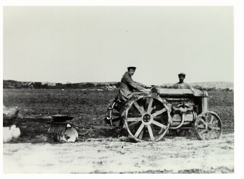 Lindhofs kungsgårds första traktor, inköpt 1924. En man sitter på traktorn och en annan står bakom ekipaget.