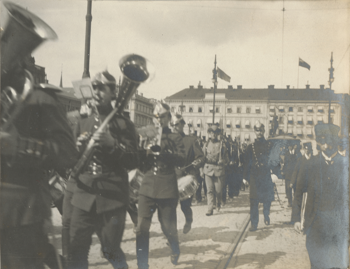 Text i fotoalbum: "Minnen från Storstrejkskommenderingen i Stockholm 1909. Jönköpings rgt:s II. komp. passerar Norrbro. Svea ing.kårs musikkår."