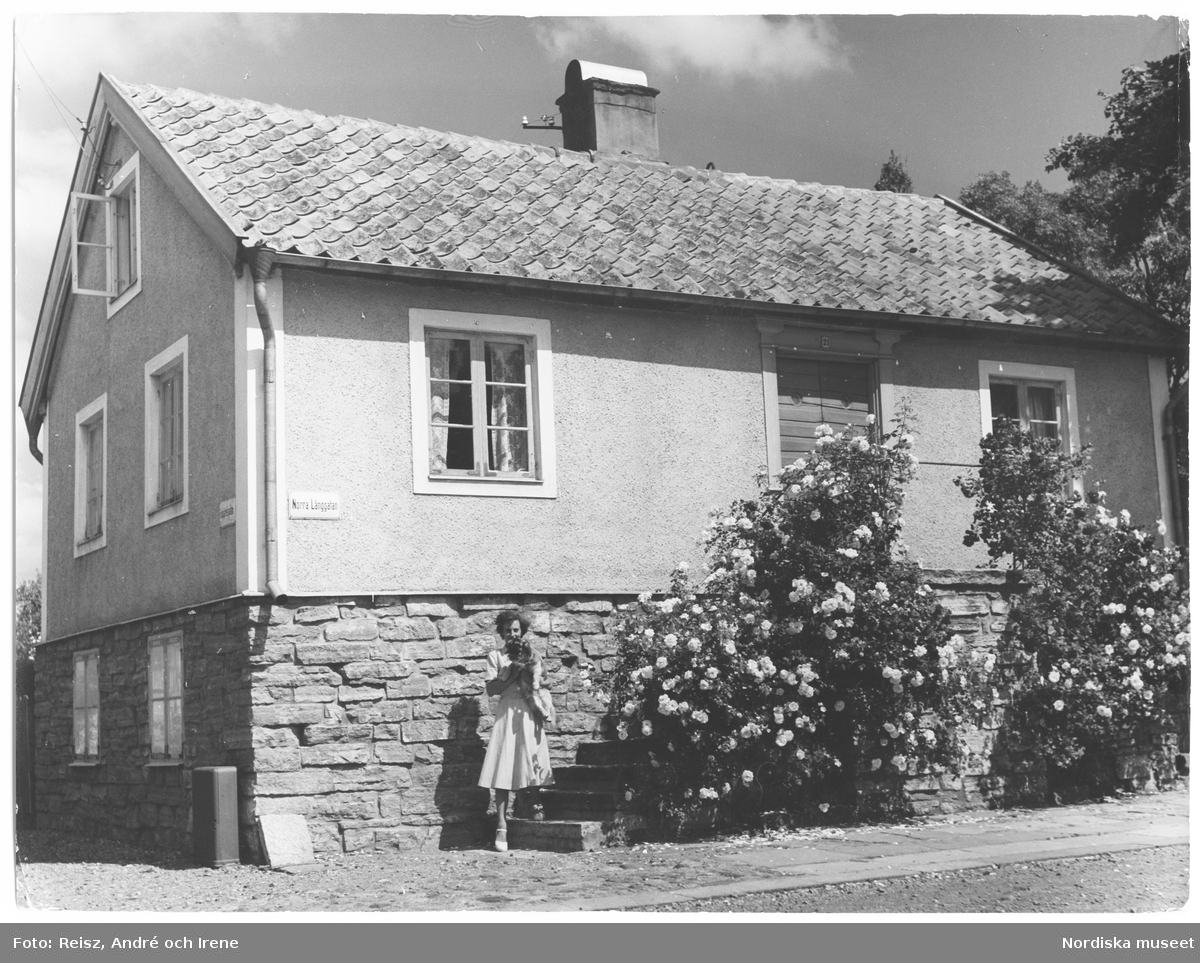 Borgholms äldsta hus på Norra Långgatan, Öland . En kvinna med vad som ser ut att vara en hund i famnen framför huset.