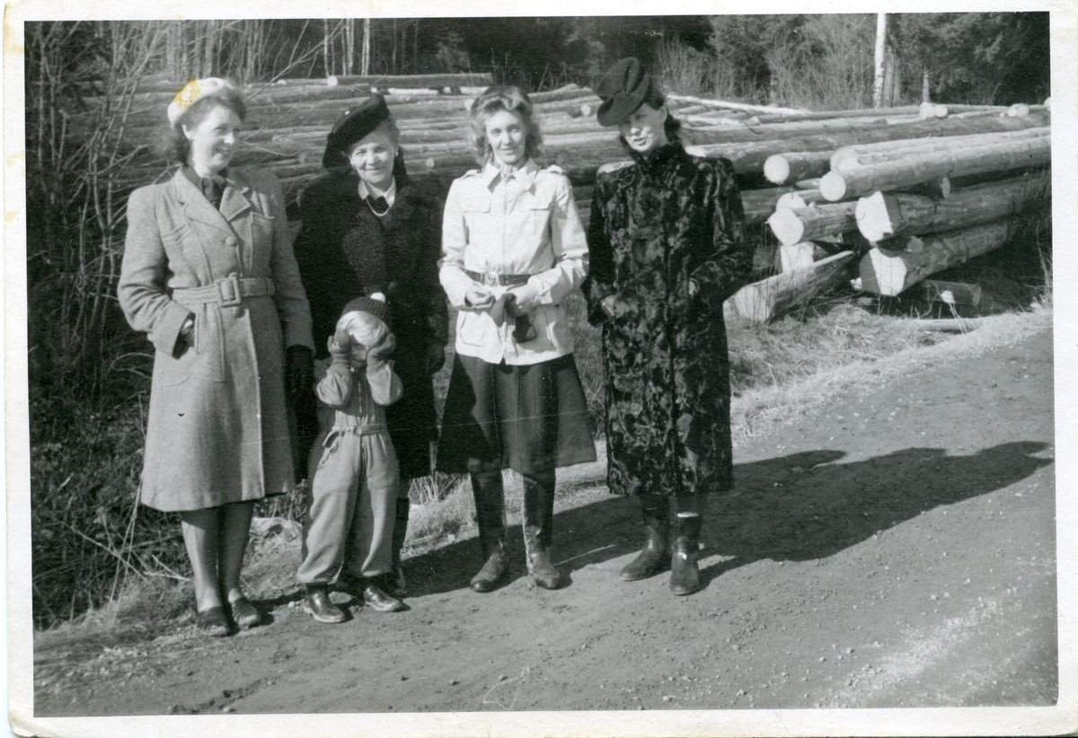 fyra kvinnor och ett barn vid timmerstockar. Ingrid Sundling till vänster i bilden.
