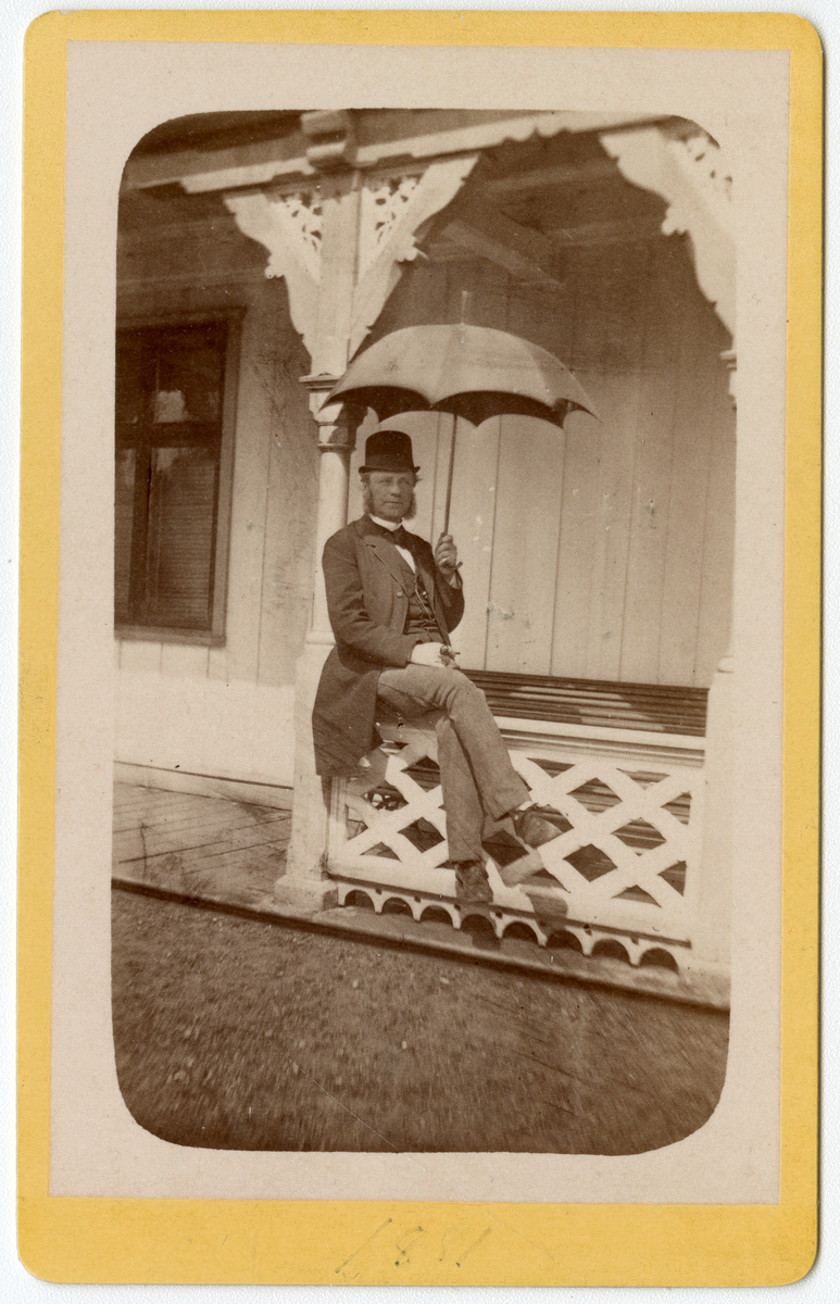 Foto av mann med parasol sittende på gelender