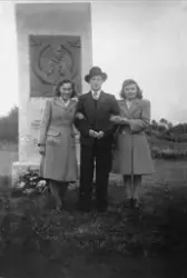 To kvinner og en mann foran bautaen til minne om falne fra S