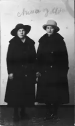 Studioportrett av to kvinner i helfigur med kåpe og hatt.