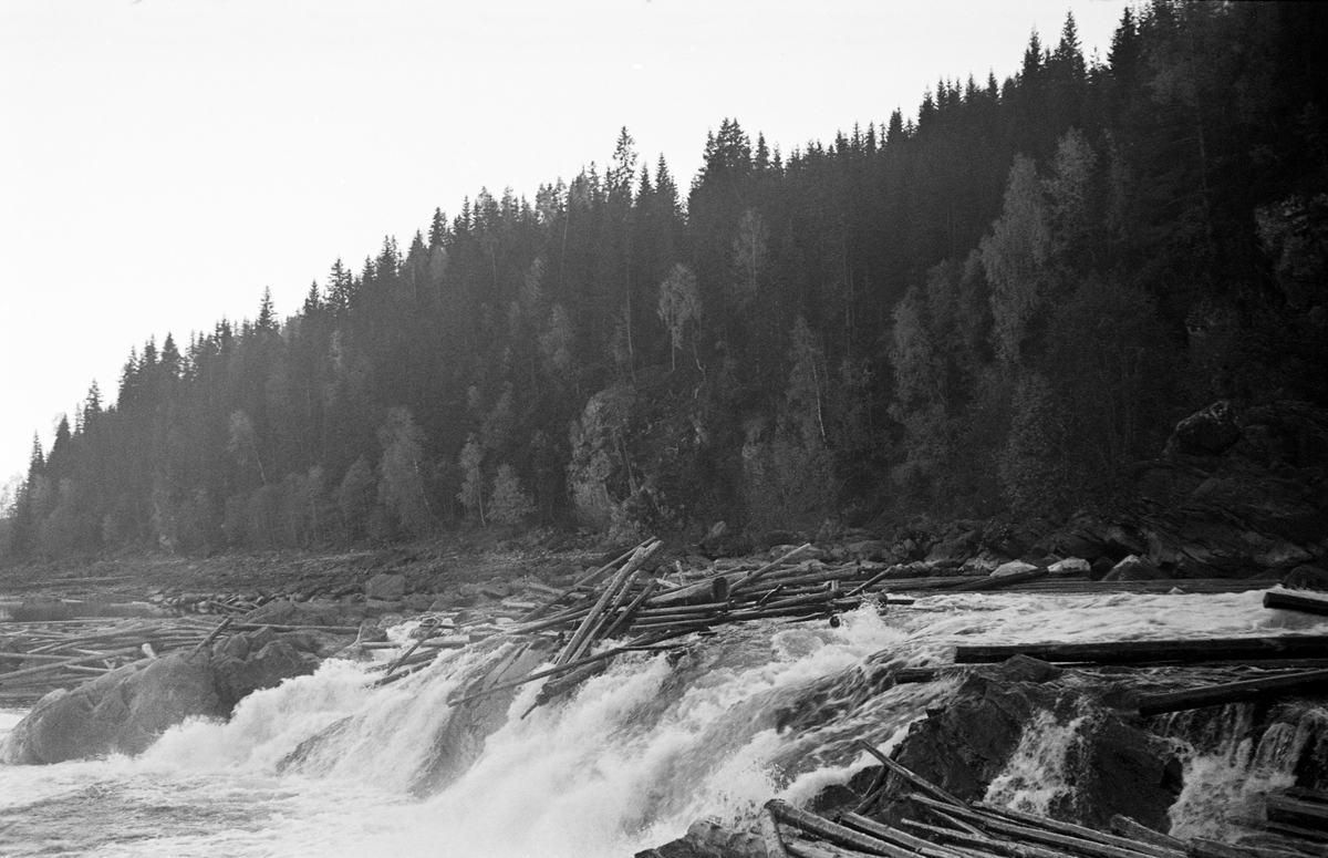 Tømmervaser i Kykkelsrudfossene i Askim i Østfold høsten 1937.  Fotografiet viser en naturlig terskel med to-tre meters høyde i elvefaret.  En del fløtingsvirke har satt seg fast akkurat ytterst på pynten mot fossen.  En del virke ligger også på bergflatene i forgrunnen og bakgrunnen.  Bakenfor en ås med gran- og bjørkeskog.

På et tidspunkt lå det en diger tømmerhaug som sperret hele elveløpet nedenfor Kykkelsruddammen. Det ble antydet at det dreide seg om 5 – 6 000 tylfter – kanskje 60-70 000 tømmerstokker. Da dette var på det verste, før dette fotografiet ble tatt, kunne en gå tørrskodd på tømmer fra den ene elvebredden til den andre. Dette hadde skjedd også to år tidligere, i 1935. Glomma fellesfløtingsforening satte inn 40 mann, de fleste lensearbeidere fra Skiptvet, for å få løsnet tømmeret. Tømmerhaugen bygde seg opp i en periode da det var liten vannføring i elva. Tilsiget til Kykkelsruddammen ble anslått til 300 kubikkmeter i sekundet, hvorav to tredeler gikk til kraftstasjonen. Fløterne ønsket seg mer vann. Dette forsøkte man å ordne ved å ofre noe av det vannet som var samlet i den ovenforliggende Solbergfossdammen. Det siste førte imidlertid til at mer tømmer satte seg fast. Bruk av dynamitt var man i utgangspunktet skeptiske til på dette stedet. Eksplosiver kunne utsette hengebrua over elva og mastene som førte elektrisiteten vekk fra kraftverket for fare, samtidig som det helt sikkert ville ødelagt mye tømmer. Likevel ble det brukt litt dynamitt. Det tok om lag to uker å få revet haugen. De store tømmerhaugene ved Kykkelsrud i 1935 og 1937 aktualiserte planene om å bygge ny dam ved denne kraftstasjonen, noe som ble realisert i perioden 1939-1941.