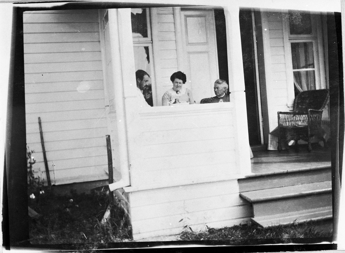 To kvinner og en mann på en veranda. Hverken personer eller sted er identifisert.
