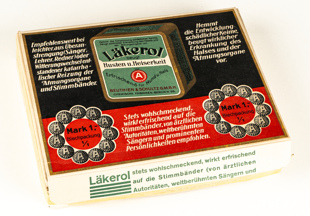 Reklamkartong med gröna Läkerolaskar i plåt. Vit kartong med svart, rött och grönt motiv samt text på tyska. Innehåller även kändisbilder