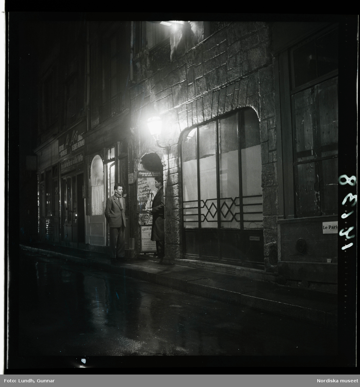 1950. Paris. Två män stående på gata kvällsbild.