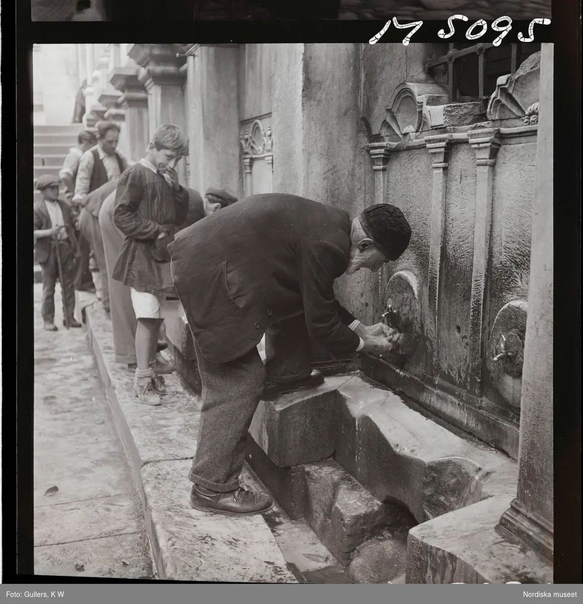 1717/L Istanbul allmänt. Män och pojke tvättar sig utanför moské.