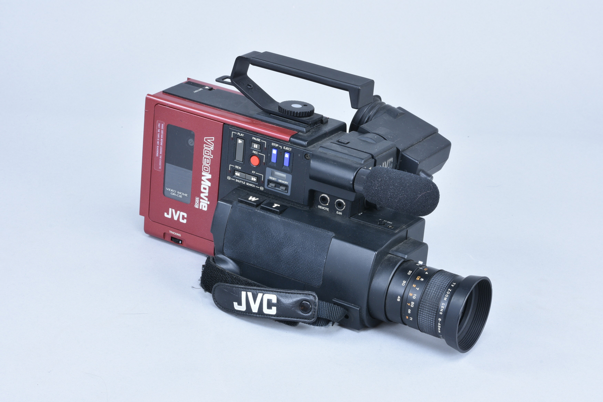 Videokamera med mikrofon och inbyggd videobandspelare för VHS-C. JVC typ GR-C1E "Video Movie", nr 110G3400.
I väska typ CB-P1U med tillhörande utrustning:
Sökare KM10057294. Batteri mod NB-P6U på 9,6 V 700 mAh. Batteriladdare JVC BB-P1EG nr 13950061 för anslutning till 110-240 V 50/60 Hz, 20 W förbrukning, 9,6 V 0,8 A = ut. RF-enhet JVC typ RF-P1U, omkopplingsbar mellan kanal 3/4. Videokablar med SCART resp. koaxialanslutning. Strömmatningssladd för 9 V=.